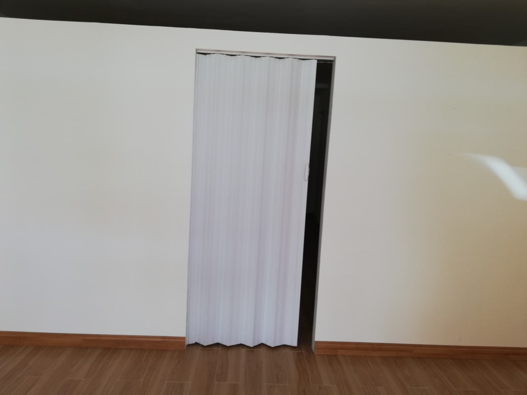 Commercial unit with beige walls and accordion folding door, wood flooring
