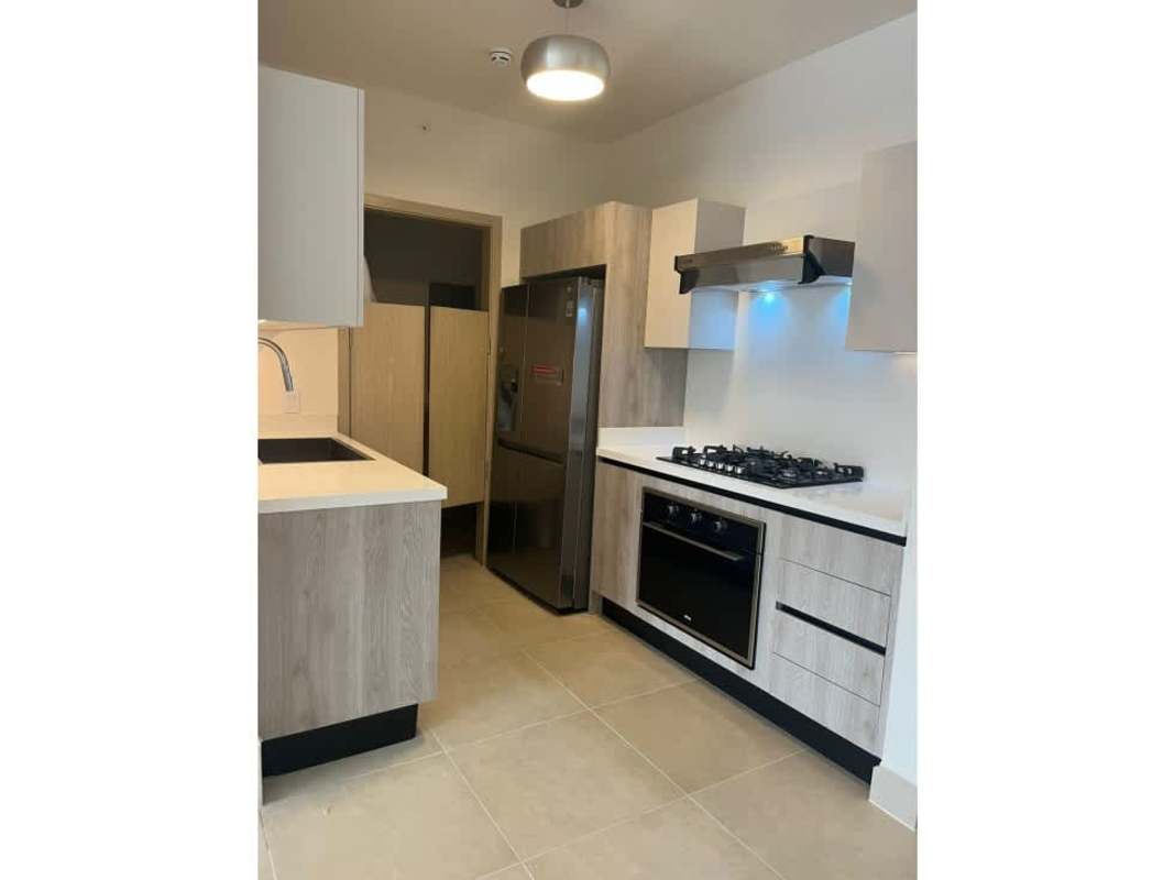 Modern open kitchen with quartz countertops and natural wood cabinetry in Ocean House Santa María Panama