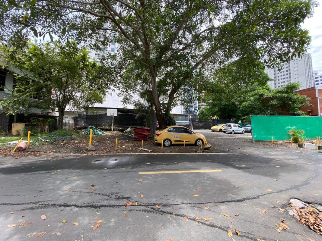 City lot with parked vehicles, shade trees, and fencing, suitable for development in El Cangrejo Panama.