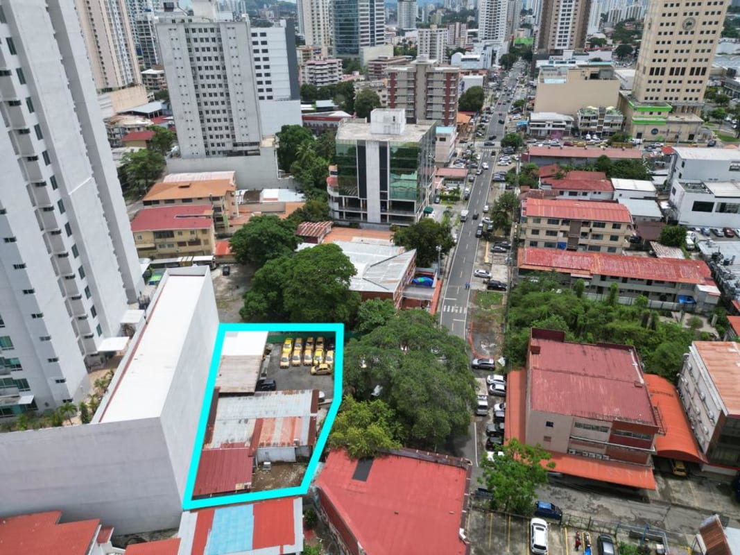 Vacant fenced lot in central Panama City with parking, trees, and close to retail and residential areas.