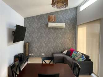 Open concept living-dining room with accent wall, TV, grey sofa Rio Hato Ibiza Beach Residences