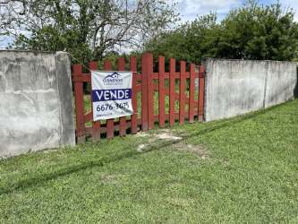 Red wooden gate, for sale sign, fenced vacant land along road Camino El Valle de Antón Panama
