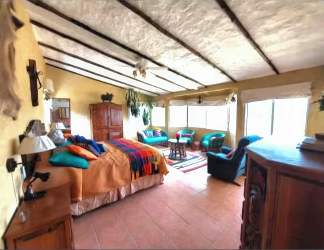 Bright rustic bedroom with large windows, terracotta tile, sitting area in El Valle country home