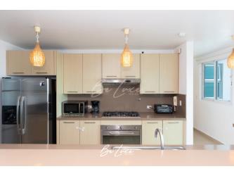 Fully equipped kitchen with beige cabinets and stainless appliances in Bijao Beachfront Condo Panama