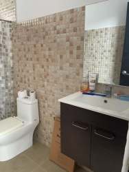 Contemporary bathroom with mosaic tiled walls, modern fixtures, and large mirror in Coronado