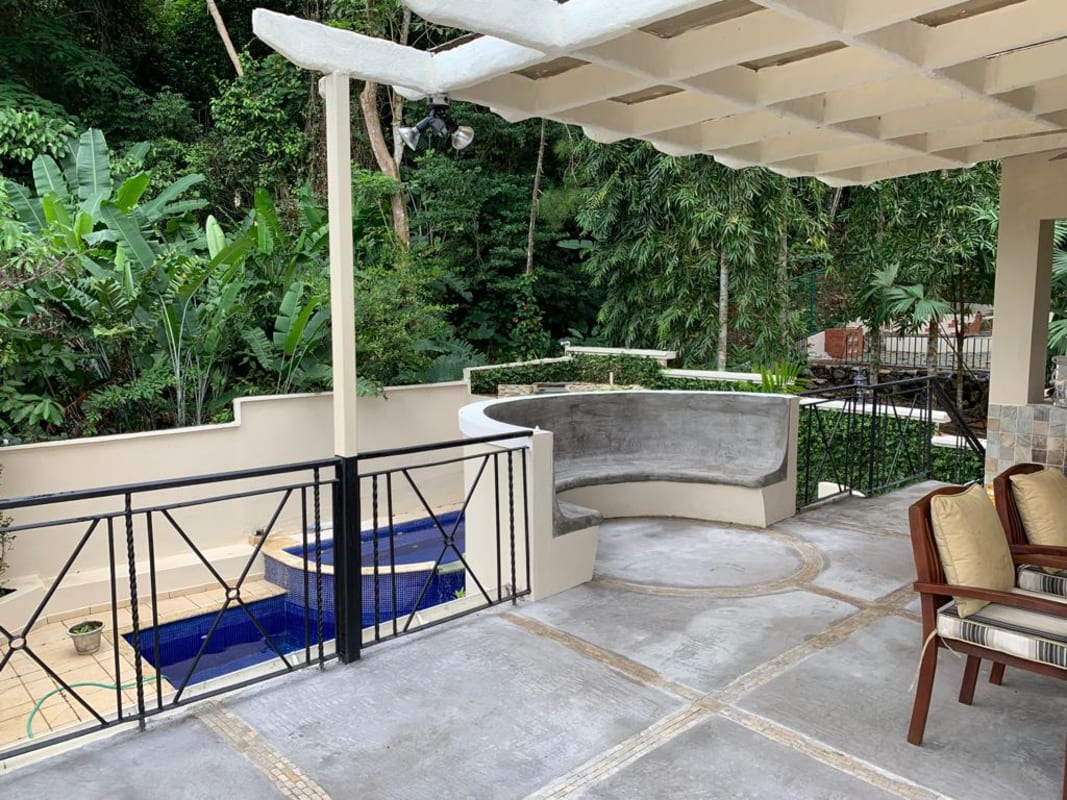 Outdoor covered terrace with built-in seating, pergola roof, view of pool surrounded by tropical greenery Albrook Panama