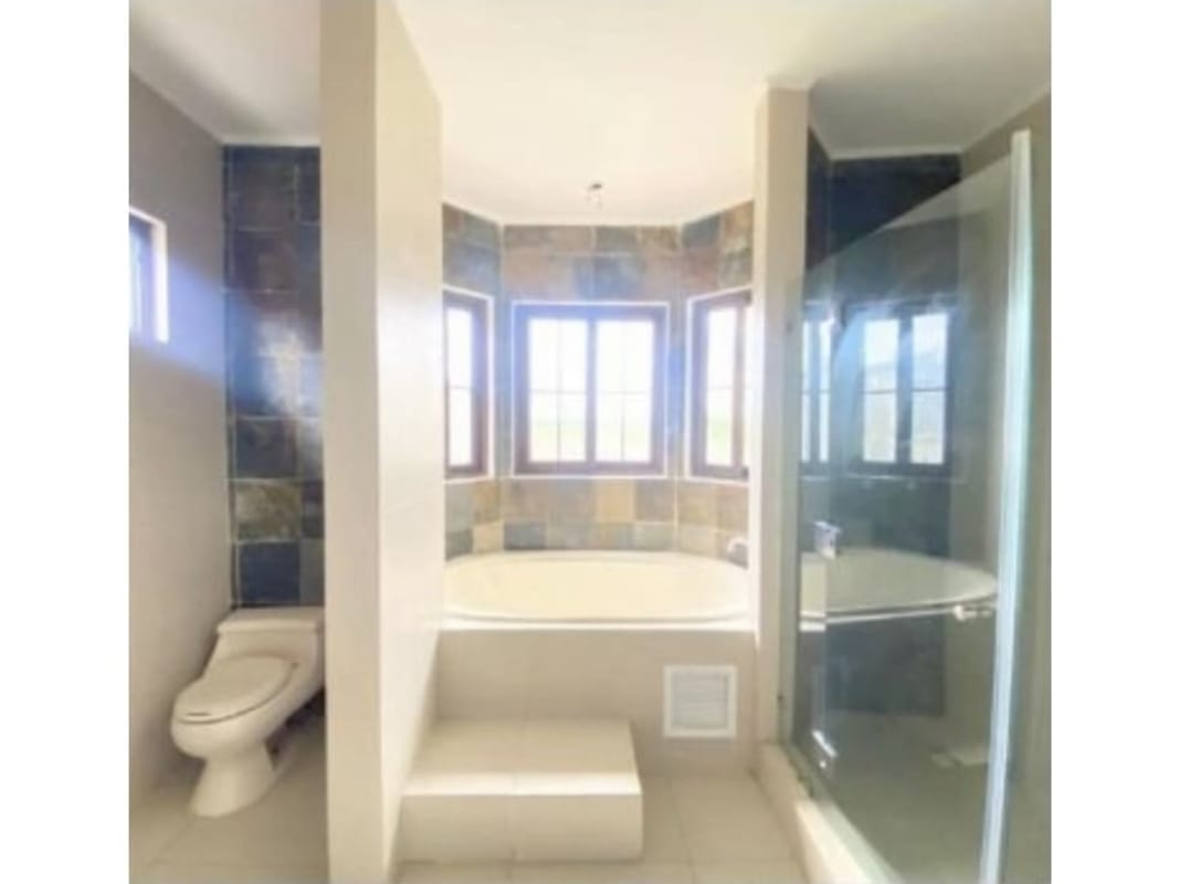 Master bathroom with step-up soaking tub, glass shower enclosure, natural light windows in Costa Linda Costa Sur Panama luxury home