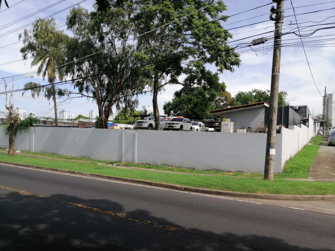 Urban lot with perimeter wall, trees, paved sidewalk, and vehicles near Avenida Santa Elena Panama City