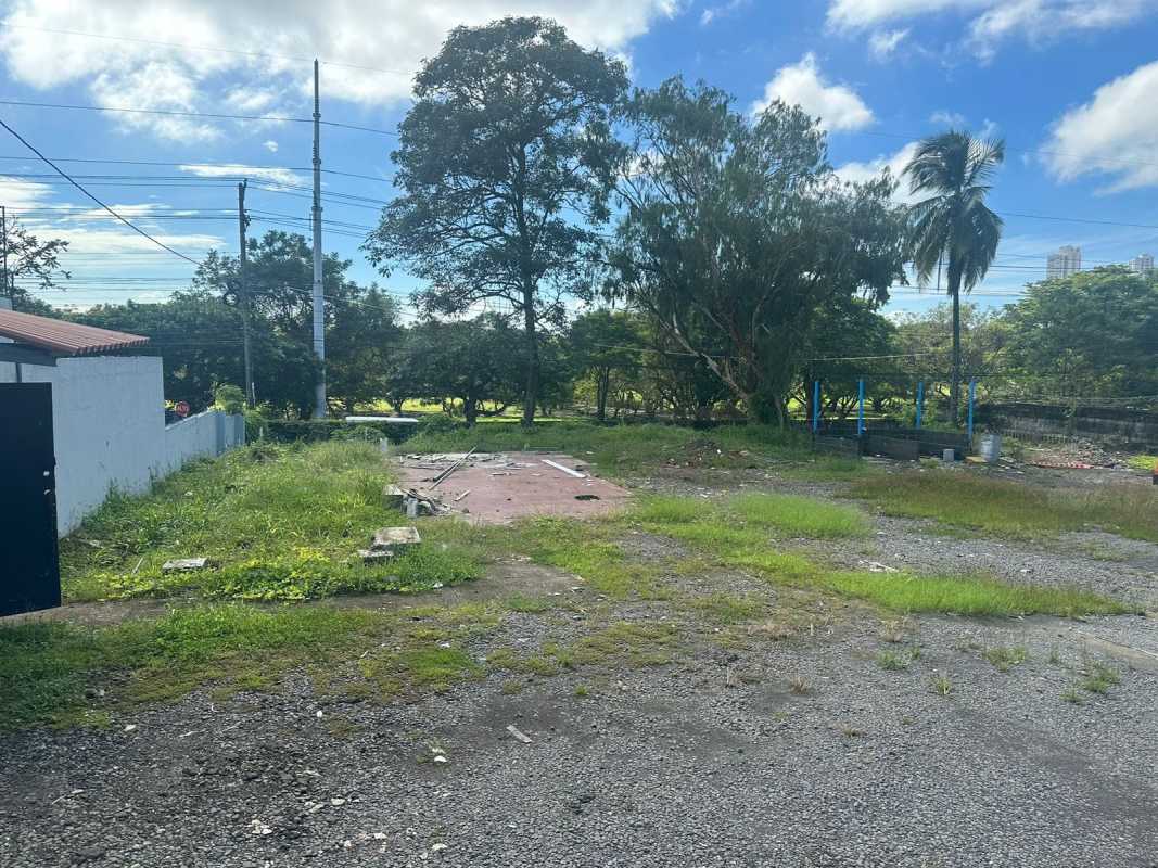 Open gravel lot with mature trees and utility poles along Avenida Santa Elena Parque Lefevre Panama City