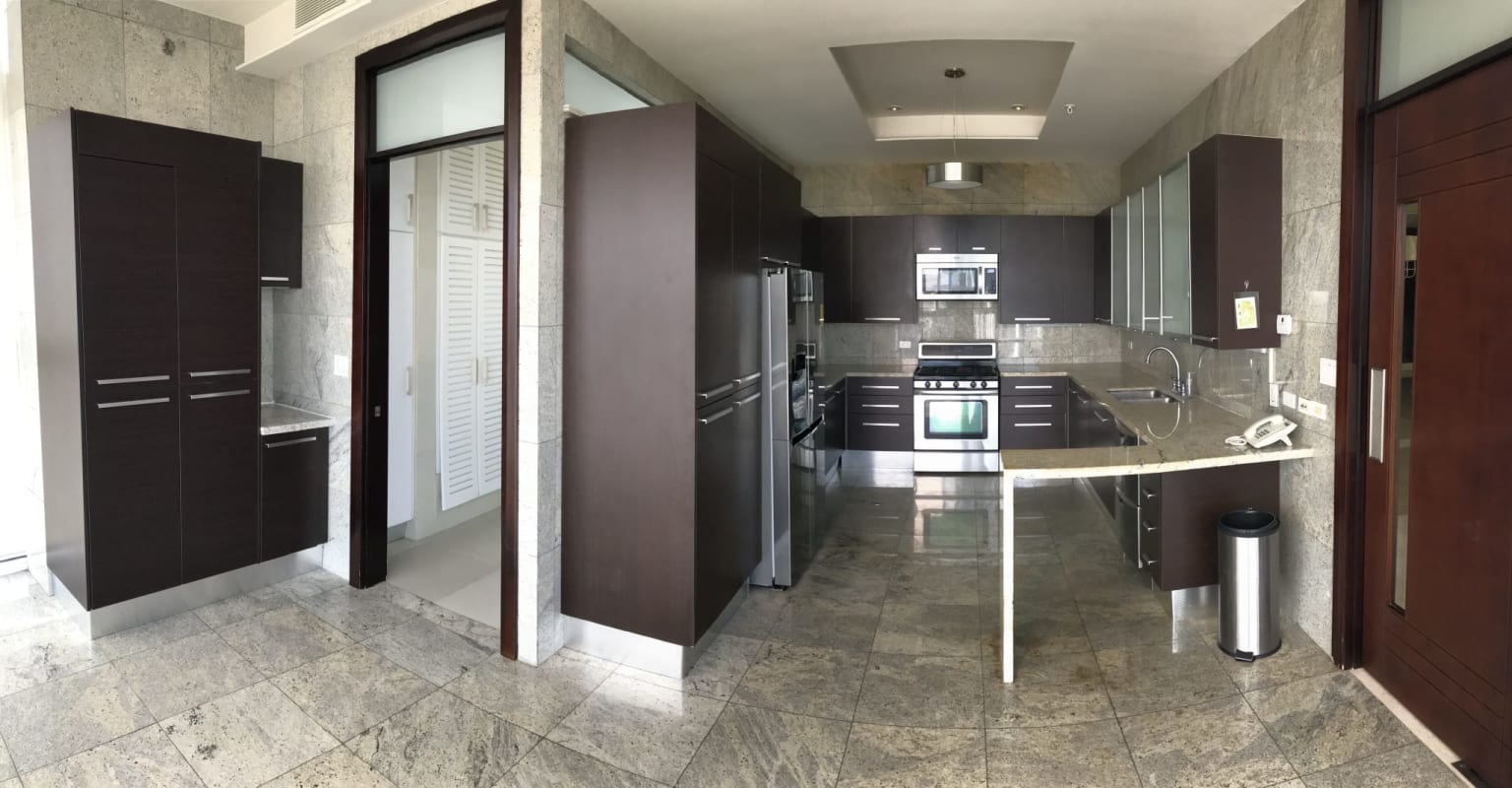 Gourmet kitchen with granite counters, wood cabinetry, and stainless appliances in The Point Punta Paitilla