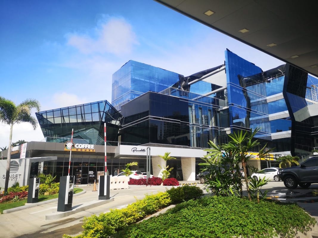 Street level view of Sunset Strip commercial plaza glass facade, parking, retail signage Panama City