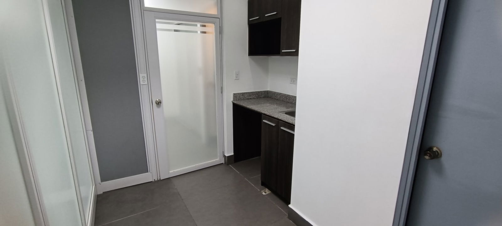 Small kitchenette with granite countertop and cabinetry inside PH Twist Tower office space