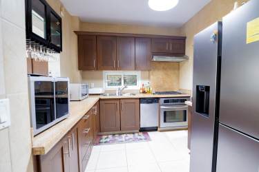 Modern kitchen with wood cabinets, granite counters and appliances in PH Tucan Country Club Arraiján Panama