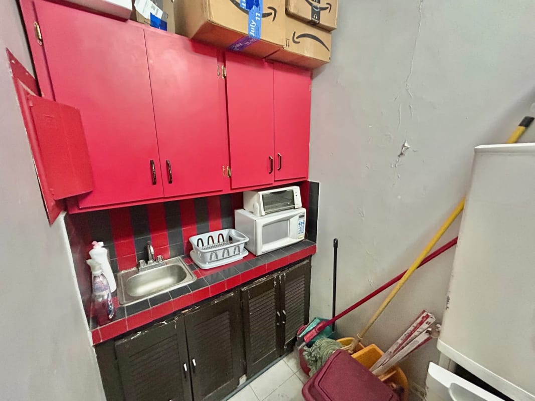 Compact kitchenette with red and black cabinets, microwave, sink in San Francisco business space Panama