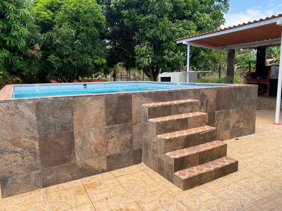 Rustic outdoor living patio with barbecue area and pool at Praderas de Utivé Pacora Panama