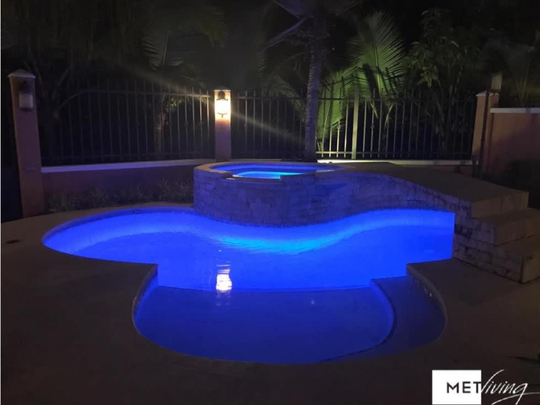 Illuminated pool and elevated jacuzzi surrounded by tropical landscaping in Clayton Village Panama