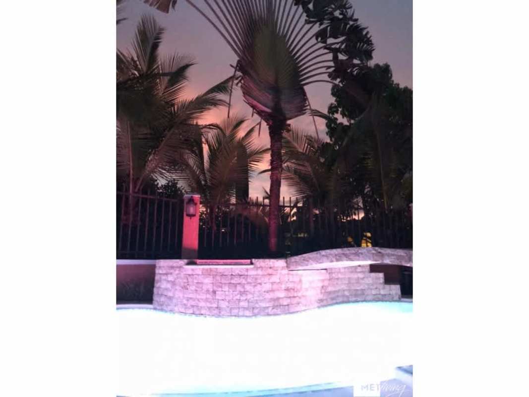 Illuminated pool area with tropical landscaping and privacy fence at Clayton Village house Panama