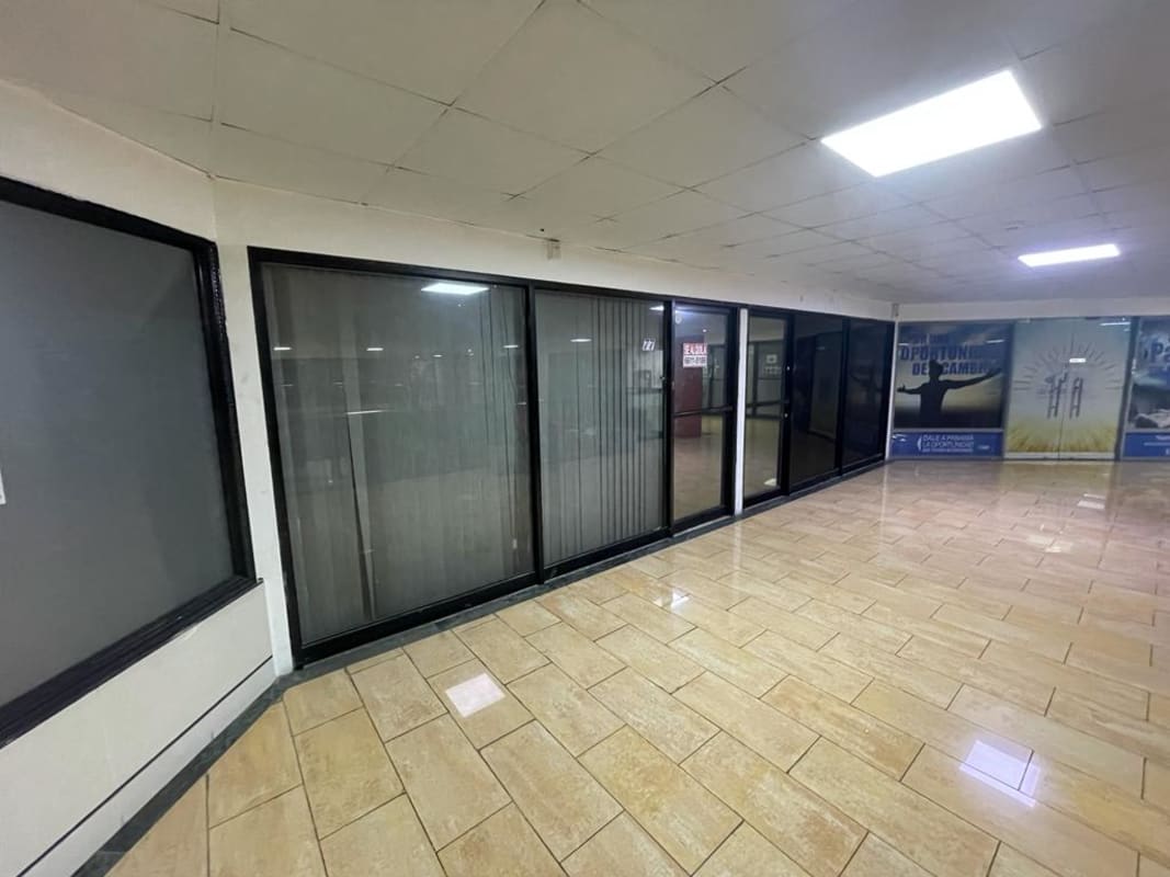 Shopping center interior hallway with glass storefronts and tile floors in Punta Paitilla commercial center Panama