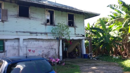 Weathered two-story wooden house surrounded by tropical vegetation in Colón