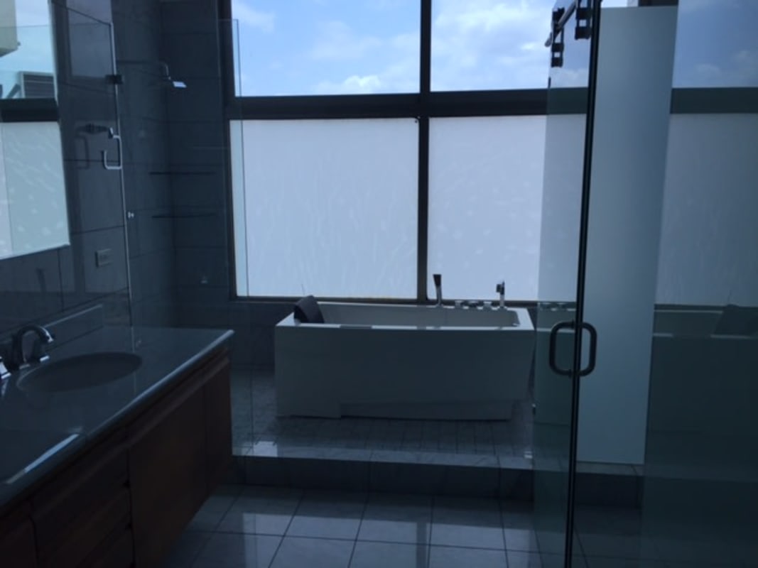 Contemporary bathroom with freestanding tub, large frosted windows, glass shower, marble walls in Punta Pacífica