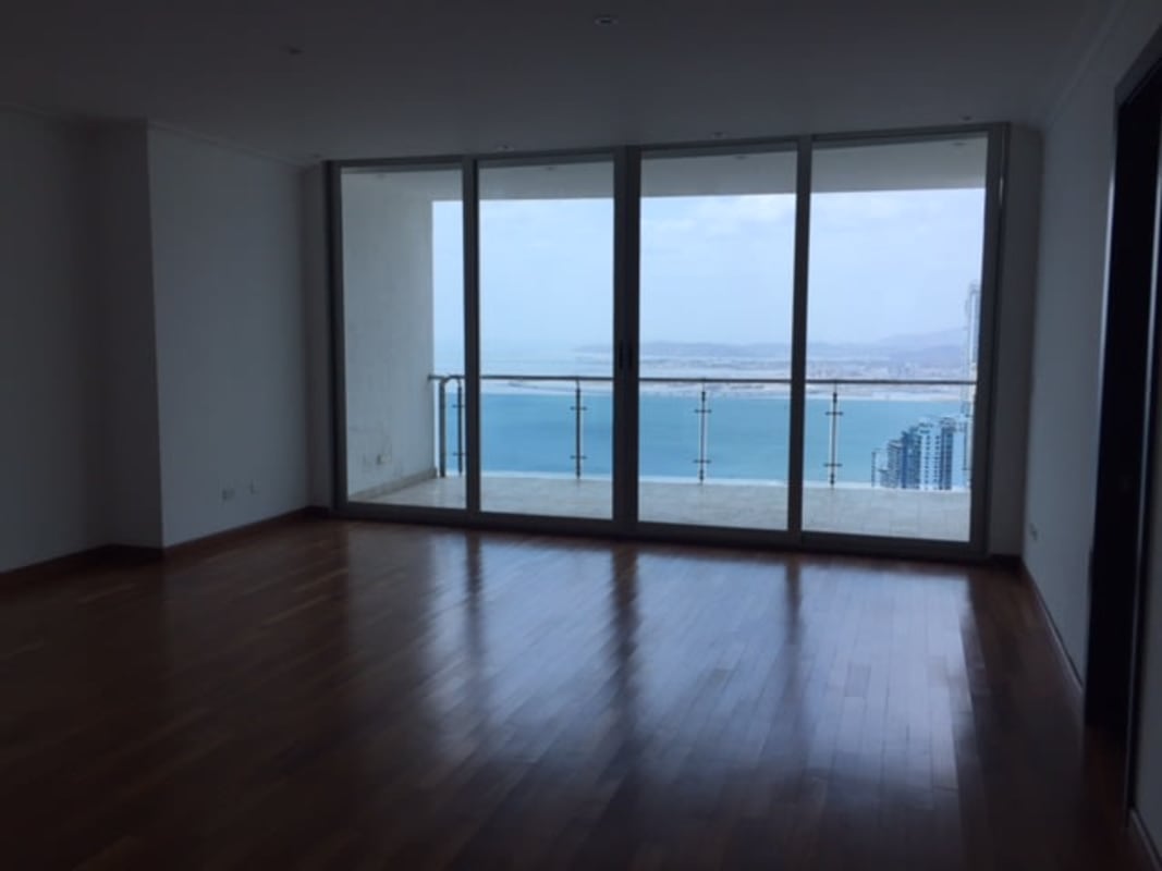 Minimalist living room with large glass doors, balcony, hardwood floors overlooking ocean in Punta Pacífica Panama