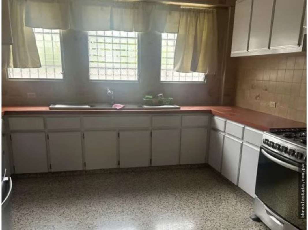 Traditional kitchen with L-shaped counters and large barred windows in Altos del Golf Panama
