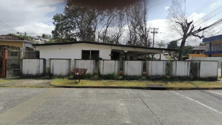 Single-story house with fenced yard, driveway, green lawn and trees in El Dorado Panama