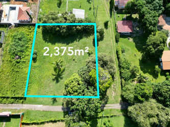 Aerial photo of large open green land with trees and neighboring houses near Playa Gorgona Panama