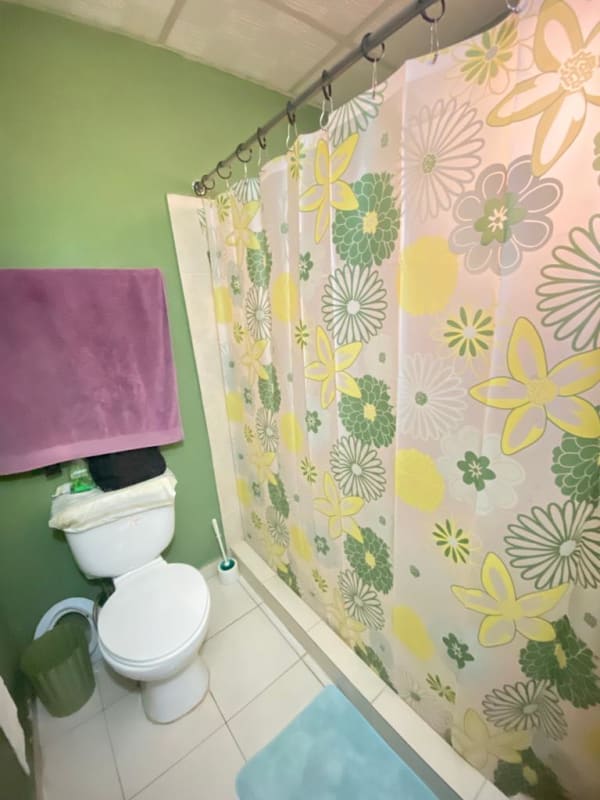 Simple bathroom with toilet shower floral curtain in Pacora Los Jardines house Panama