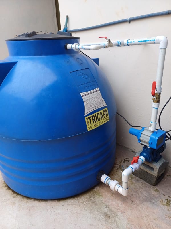 Blue water storage tank with pump system on cement base outdoors in Pacora residential house