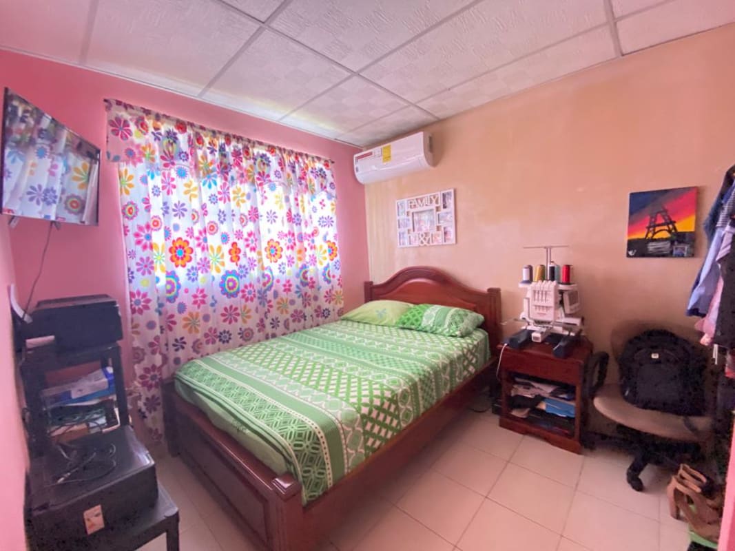 Bedroom with split AC, colorful curtains, green bedspread in Pacora Los Jardines affordable house
