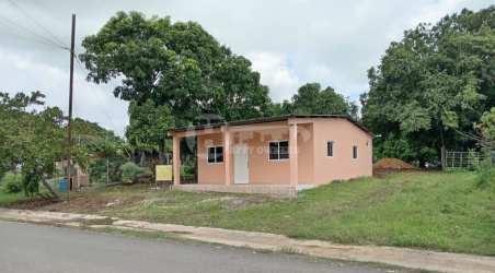 One story peach house with porch surrounded by trees grassy yard San Jose Panama