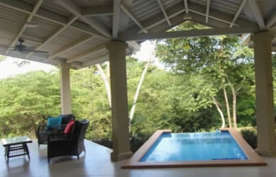 Evening view of lit swimming pool with view into modern kitchen in El Espino Panama