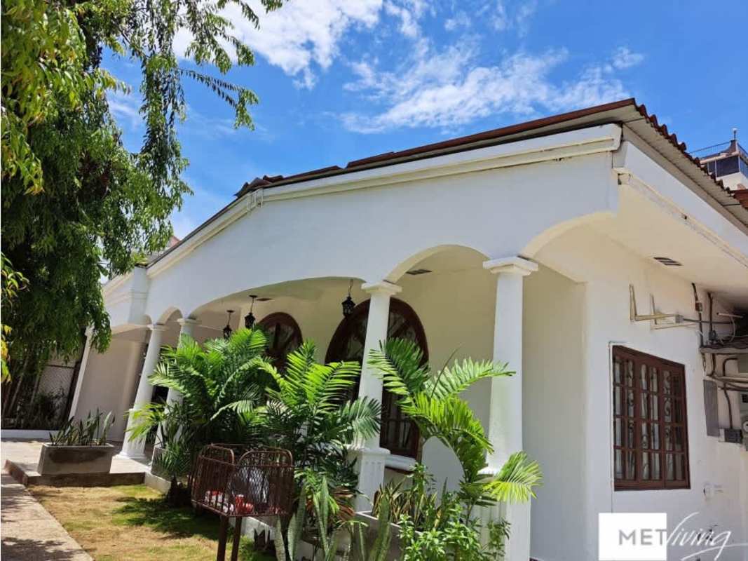 Elegant villa with arched porch, white facade, lush landscaping in Obarrio Panama City for sale