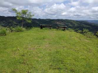 Hilltop with wooden benches overlooking green mountains in Buena Vista Colón farmland