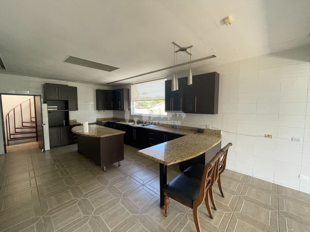 Contemporary kitchen with granite countertop island, dark wood cabinets and modern lighting in Dos Mares home Panama