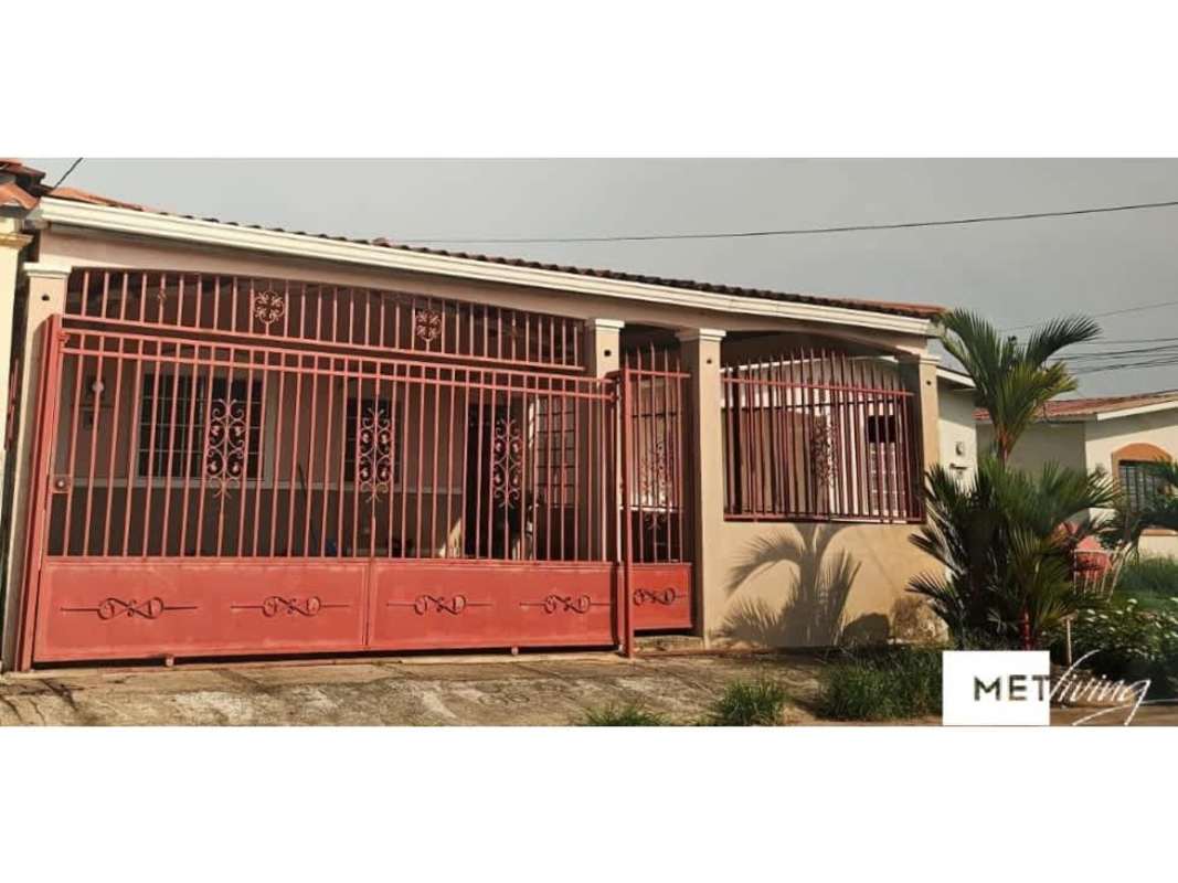 View of house with red iron gate, barred windows, garden palm trees in Viña del Mar Panama