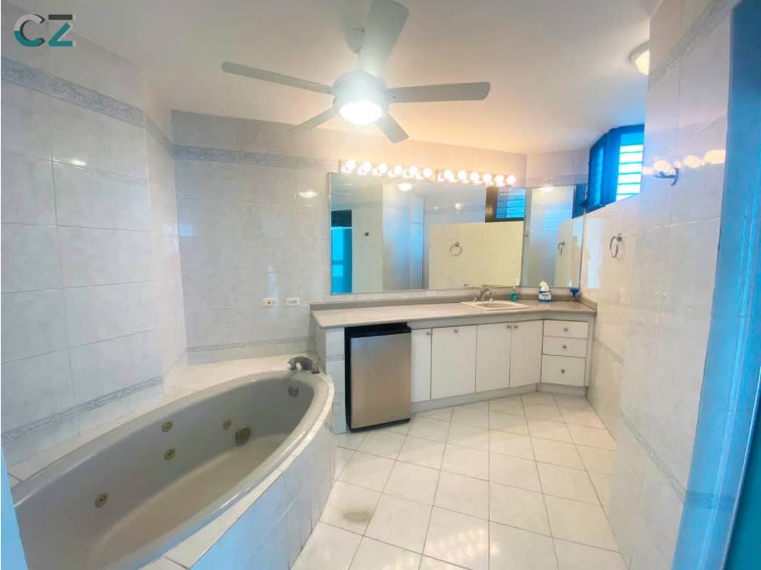 Bright minimalist kitchen with white cabinetry, fridge and appliances at PH Costa del Mar Panama