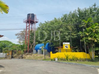 Community water tank infrastructure with yellow building and palm trees inside Las Uvas Gated Community near San Carlos Panama