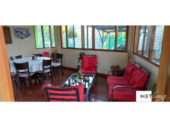Sunroom with large windows, red cushions and dining area at Gorgona Beachhouse Panama
