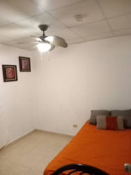 Simple furnished bedroom with ceiling fan, closet and orange bedding for women rental in La Chorrera