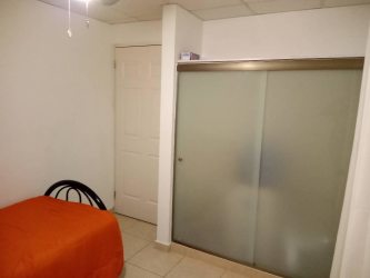 Bedroom with frosted closet doors, orange bedding, ceiling fan in La Chorrera women's room rental