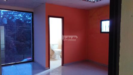 Compact office interior with private bathroom, orange accent wall, and glass window Chitré Veraguas