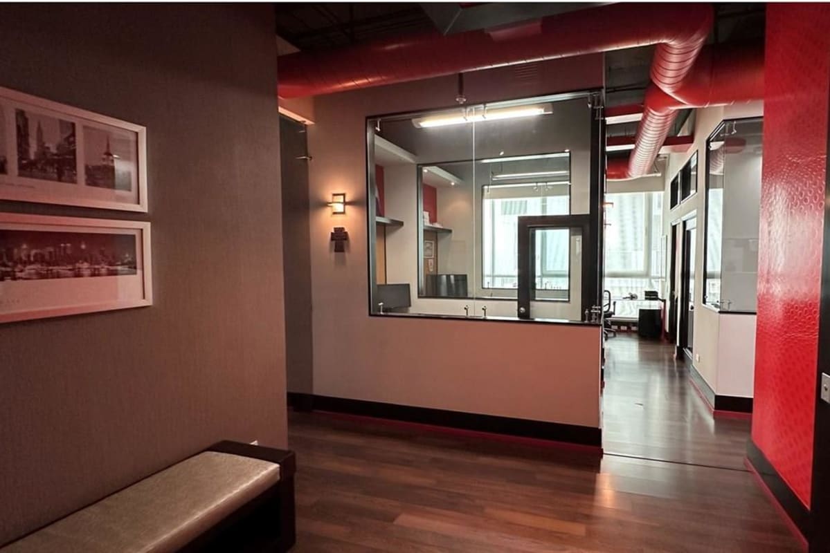 Modern office corridor with glass partition, wood floors, and exposed red duct in PH Blue Business Center San Francisco Panama