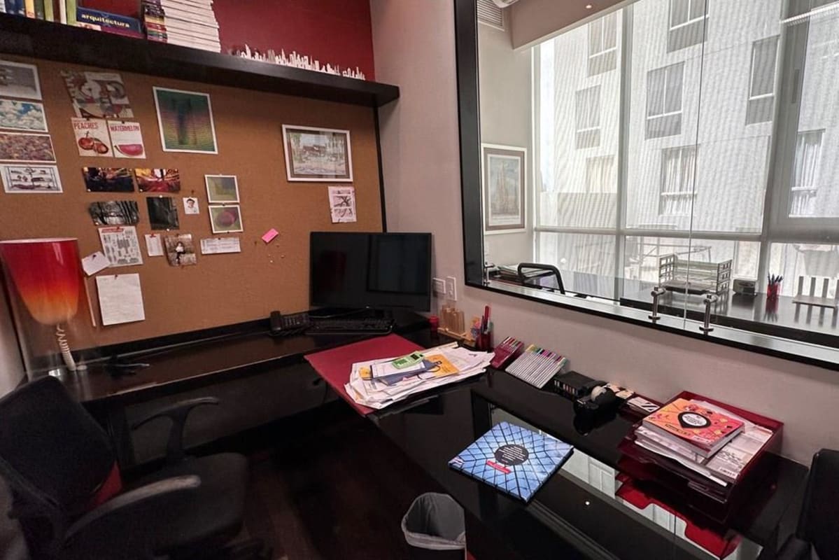 Office workspace with L-shaped desk, glass partition, bulletin board, and shelves PH Blue Business Center Panama City