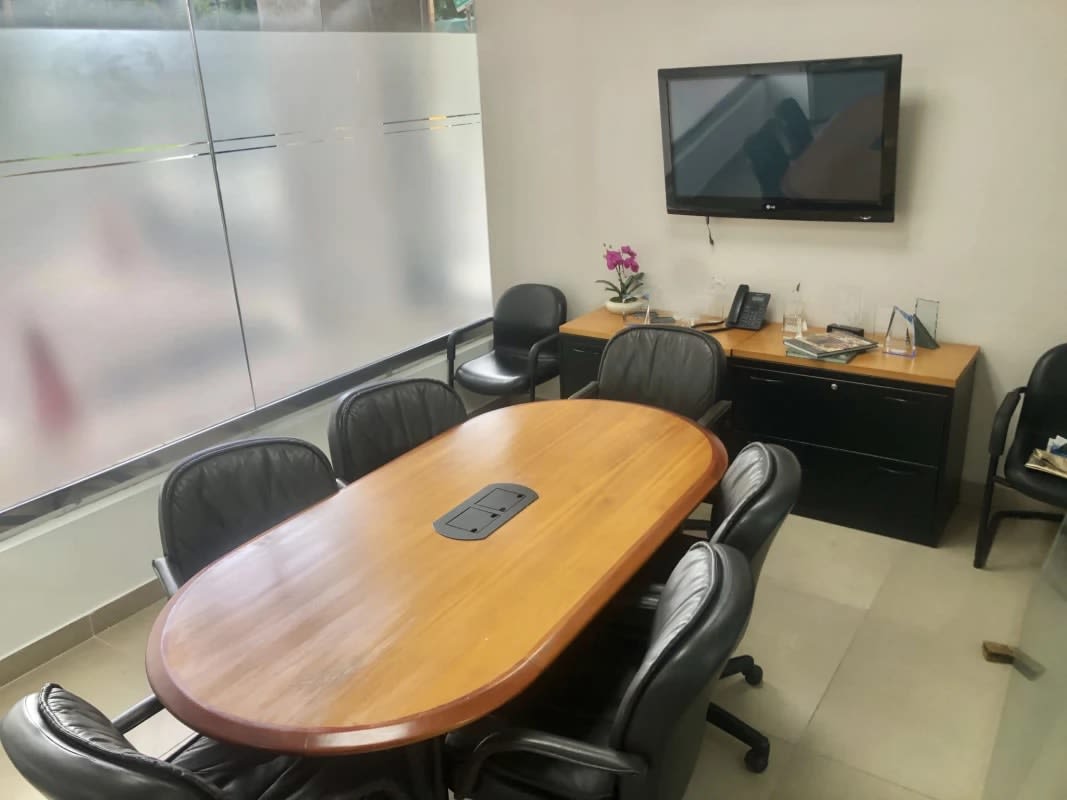 Glass-enclosed meeting room with TV, conference table and black chairs in Punta Paitilla office rental Panama