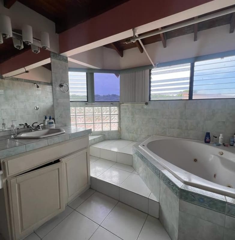 Bathroom with jacuzzi step-up platform large windows wood beams Villa de las Fuentes