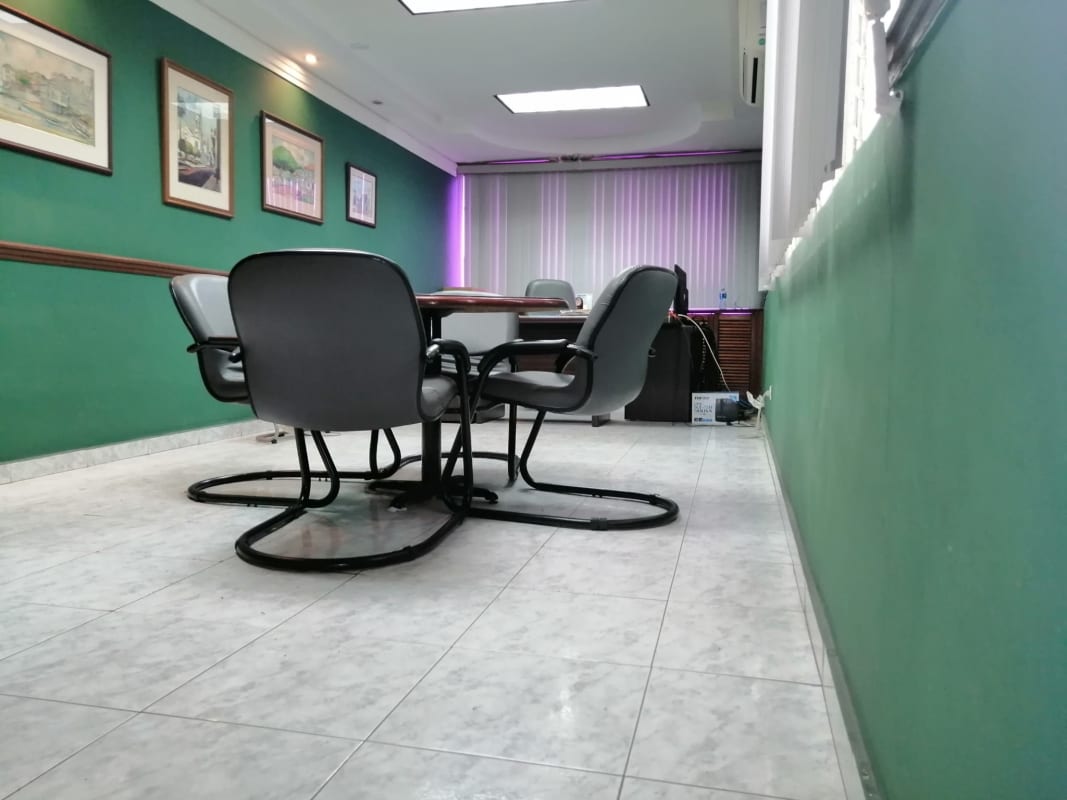 Narrow hallway leading to office reception with white chairs, flower arrangement Obarrio Panama