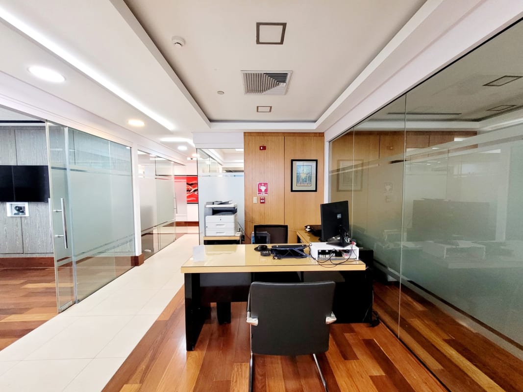 Executive private office space featuring glass wall dividers and city views in BICSA Tower