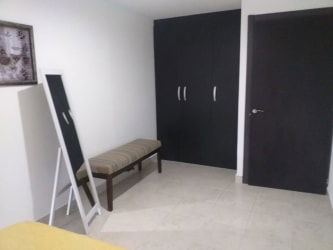 Minimalist bedroom with dark wardrobe, bed, mirror, tiled floor in PH Ibiza Playa Coronado beach Panama